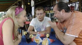 Stefan (Mathias Schlung, M.) versucht Marie (Janine Kuinze, l.) und Bernd (Markus Majowski, r.) davon zu überzeugen, dass der Film "Ein Fisch namens Wanda" nicht lustig ist, indem er sich Pommes in die Nase stopft und einen Fisch isst - was dann sehr lustig ist ... © Sat.1