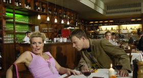 Mirja (Mirja Boes, l.) nimmt als gelangweilte Ehefrau ihren Lover überall hin mit - sogar im Restaurant muss er sich zum Erstaunen von Mathias (Mathias Schlung, r.) unter dem Tisch verstecken. © Sat.1